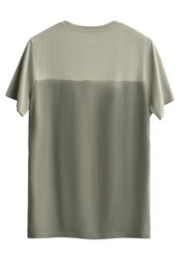 T-shirt verde oliva realizzata in tessuto morbido. Maniche corte, colletto rotondo e effetto sfumato con una parte superiore più chiara. Vestibilità leggermente ampia.