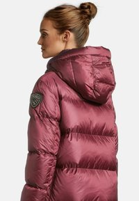 Bordeauxfarbene Pufferjacke mit Kapuze, verfügt über ein gestepptes Design, glänzende Textur und ein Logopatch am linken Ärmel.