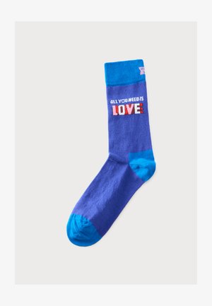 Niebieska skarpetka z jaśniejszym niebieskim piętą, palcem i mankietem, z tekstem "ALL YOU NEED IS LOVE" w białych, różowych i czerwonych literach na mankiecie.