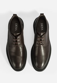 Chaussures en cuir brun foncé avec une finition lisse, dotées d'un design à lacets, d'un bout rond et d'une semelle en caoutchouc noir texturé. Nom de la marque : DESA.