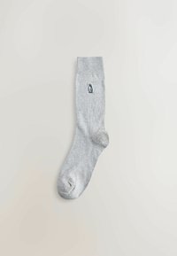 Pilka medvilninė kojinė su įmantria apatine dalimi, šone esantis nedidelis juodas ir baltas pingvino logotipas. Minkšta tekstūra ir standartinė kulkšnies ilgis.