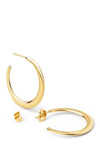Boucles d'oreilles en métal doré avec un design lisse et courbé, dotées d'une fermeture à tige sécurisée. Elles présentent une surface brillante et réfléchissante.