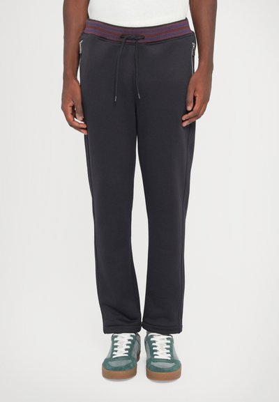 Pantalones de chándal navy con una cinturilla acanalada y cordón ajustable. Bolsillos laterales con cremallera y diseño de pierna estrecha. Tejido suave con textura lisa.