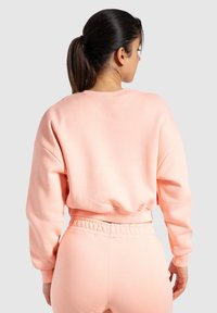Lichtroze, oversized sweatshirt met een ronde hals en geribbelde manchetten. Zacht, gestructureerd materiaal past bij de bijpassende elastische taillebroek.