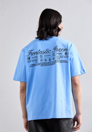 Blue cotton T-shirt featuring black printed text and icons on the back, including brand names and sustainability messages.