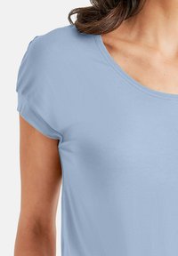 Lichtblauw kortarm t-shirt met een ronde hals, gemaakt van zacht materiaal met een gladde textuur en subtiele stikdetails.