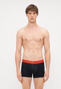 Boxeri negri cu talie roșie, având inscripția "NIKE" în litere aurii. Material moale și elastic, conceput pentru confort și o fixare perfectă.