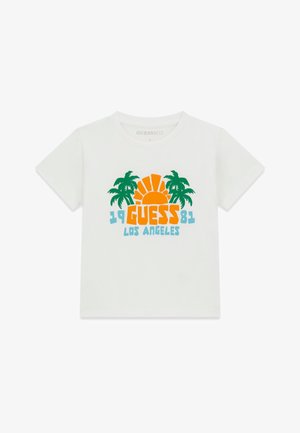 T-shirt blanc à manches courtes avec des palmiers verts, un soleil orange et un texte bleu "1981 GUESS LOS ANGELES" sur le devant.