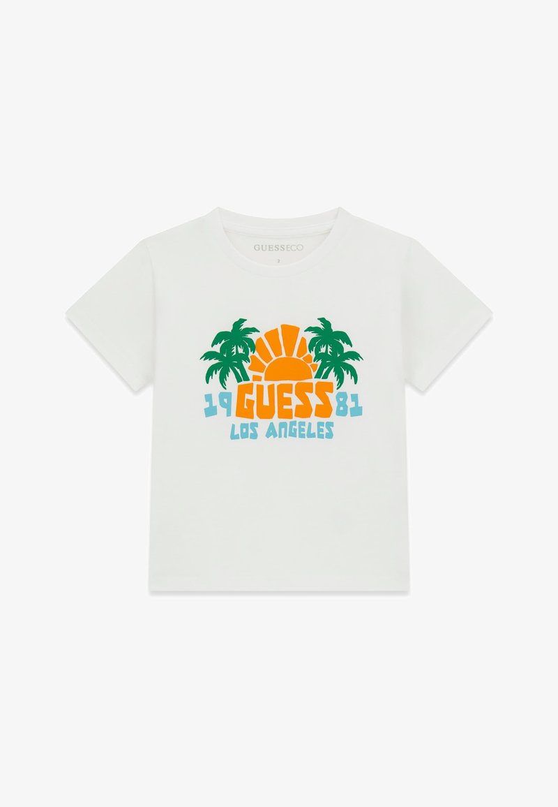 T-shirt blanc à manches courtes avec des palmiers verts, un soleil orange et un texte bleu "1981 GUESS LOS ANGELES" sur le devant.