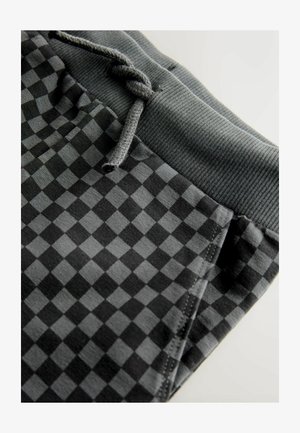 Zwarte en grijze geruite joggers met een geribbeld tailleband en trekkoord. Kenmerkt zich door een gladde stof met een matte textuur.