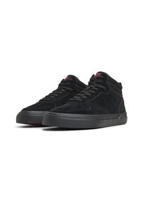 Une paire de baskets montantes noires avec une texture en suede, des lacets noirs, une semelle épaisse et des détails de logo rouges sur la languette et sur le côté.