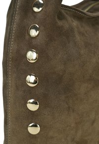 Wildleder-Shopper in Braun mit sechs metallisch silbernen Nieten an einer Seite. Weiche Textur mit gesteppten Details. Einfaches, funktionales Design.