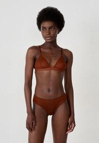 Braun mit Spitze verziertes Bralette mit verstellbaren Trägern, kombiniert mit hochgeschnittenen passenden Slips, die ein dezentes Strukturmuster aufweisen.