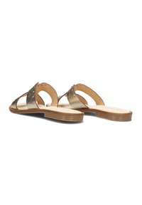 Gold metallic sandals with open toe design, featuring wide straps, circular cutouts, and flat natural colored sole. Smooth leather texture.