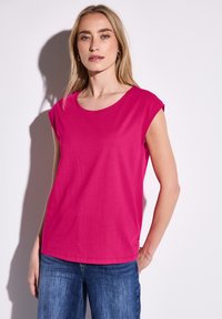Fuchsiové tričko s krátkým rukávem a kulatým výstřihem, vyrobené z lehkého materiálu. Disponuje uvolněným střihem a hladkou texturou.
