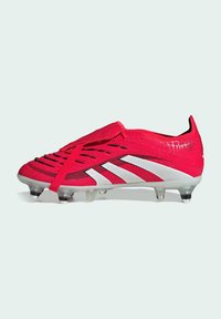 Röd fotbollssko med en texturerad ovandel, elastiskt snörsystem, tre vita ränder och en genomskinlig sula med svarta dobbar.