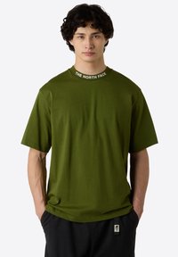Olivegrünes T-Shirt mit kurzen Ärmeln aus weichem Stoff, mit rundem Halsausschnitt und der Aufschrift "THE NORTH FACE" in Weiß.