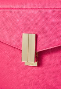 Różowa, fakturowana torebka z metalicznym, złotym zapięciem. Projekt charakteryzuje się czystymi liniami i usztywnionym kształtem z klapką zamykającą.
