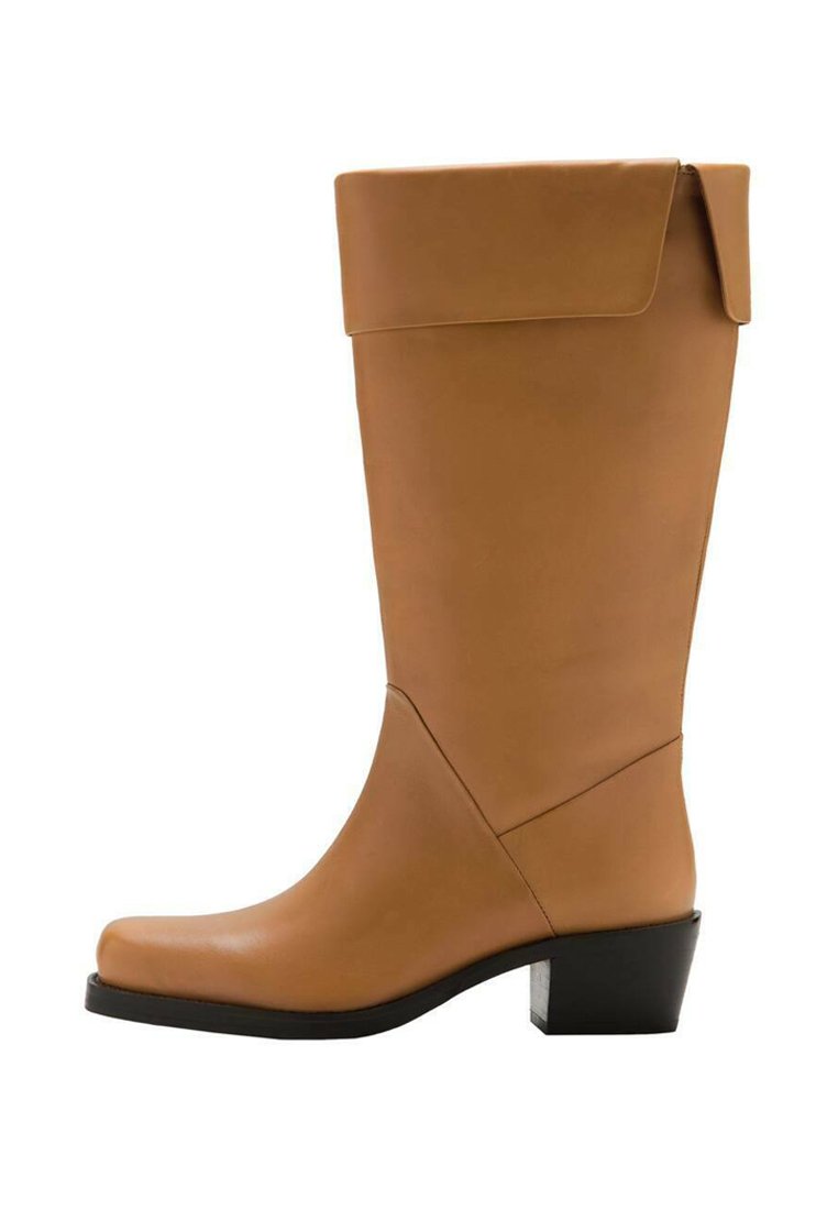 Botte haute couleur caramel avec un bout arrondi, texture en cuir lisse et un talon épais noir. Elle présente un revers replié en haut.