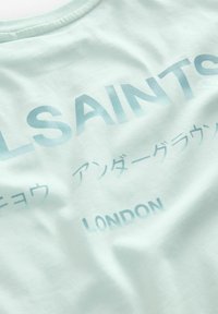 Šviesiai mėlynas medvilninis marškinėlis su iškiliais įvairių atspalvių tekstais "ALLSAINTS" ir "LONDON", o apačioje dar keli simboliai.