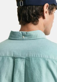 Lichtgroen shirt met een button-down kraag, met een inzet en plooi detail op de rug. Gemaakt van zachte, gestructureerde stof.