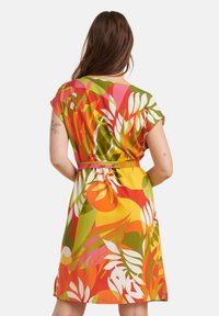 Kortgeloofde jurk in levendige kleuren, met een tropisch bloemenpatroon. Gemaakt van lichtgewicht stof met een tailleband voor een getailleerde pasvorm.