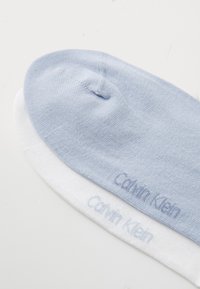 Lysblå og hvide sokker med en blød tekstur. Har "Calvin Klein" logo i lysblå på begge. Rundt tå-design.