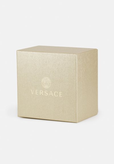 Zlatá, textúrovaná darčeková krabička s lesklým povrchom. Na prednej strane sa nachádza výrazné embosované logo "Versace" a kruhový dizajn.