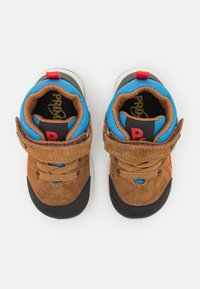 Sneakers din suede maro cu accente textile albastre, talpă din cauciuc negru, închidere cu bretele și detalii roșii ale logo-ului pe limbă.