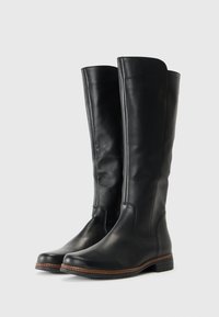 Bottes noires en cuir, montant jusqu'au genou, avec une texture lisse, un bout rond et des détails de semelle cousue marron. Design minimaliste sans quincaillerie visible.