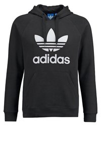 Svart hoodie tillverkad av mjukt tyg med en känguruficka. Har en stor vit Adidas-logotyp och tre randar på bröstet och huvan.