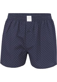 Boxers en coton bleu marine avec des pois blancs, dotés d'une taille élastique, d'un bouton à l'avant et d'une étiquette portant la mention "MG" près de la taille.