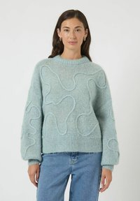 Jasnoniebieski sweter z dzianiny z teksturowanym falistym wzorem, z prą�żkowanym dołem i mankietami, z okrągłym dekoltem i luźnym krojem.