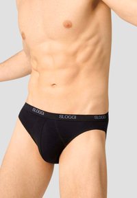 Slip SLOGGI neri con un morbido elastico in vita che mostra il nome del marchio, caratterizzati da un taglio classico e una texture di tessuto liscia.