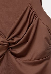 Top in tessuto marrone con design annodato al centro, caratterizzato da dettagli arricciati ai lati e una finitura liscia e testurizzata.