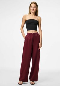 Svart strapless topp med en kort design, ihop med högmidjade vida burgundy byxor med knapp fram och fickor på sidan.