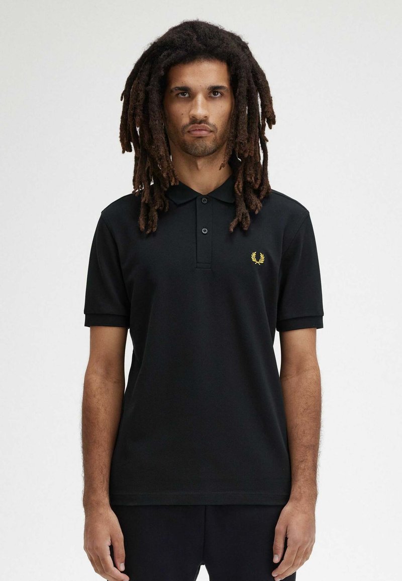 Polo shirt nero a maniche corte, con patta a due bottoni e logo ricamato in oro sul lato sinistro del petto. Tessuto morbido con una vestibilità comoda.