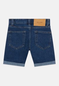 Denim kratke hlače temno modre barve s preklopom na robu. Imajo dve zadnji žep in svetlo rjavo usnjeno oznako na pasu. Vidni so detajli šivanja.