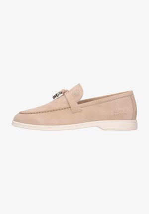 Beige suede loafer with a low profile, contrasting white sole, decorative strap and metal hardware detail. Features embossed logo on side.