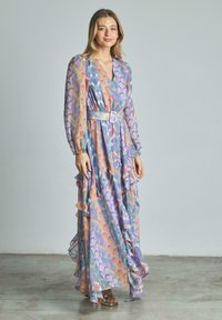 Langes, fließendes Kleid in Pastellfarben mit geometrischen Mustern. Aus leichtem Gewebe, mit Rüschen und einem taillierten Schnitt.