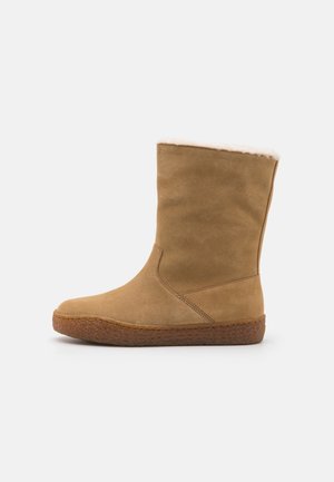 Brązowe zamszowe botki na kostkę z miękką kremową ociepliną, zaokrąglonym czubkiem, gumową podeszwą i detalami wzdłuż bocznych szwów.