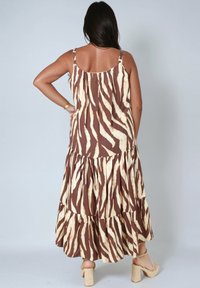 Bruine en crèmekleurige maxi-jurk met tiered ontwerp in een zebra-print, met spaghettibandjes en een vloeiende silhouet.