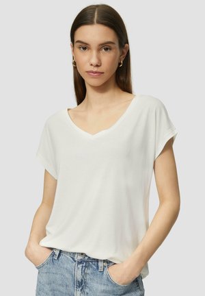 T-shirt blanc à manches courtes et col en V, en tissu doux, avec une coupe décontractée et une texture lisse, associé à un jean bleu clair.