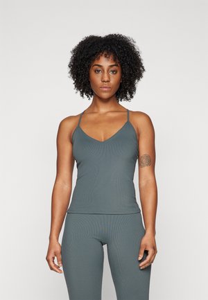 Gray ribbed tank top with thin straps and a V-neck design, paired with matching leggings. Features a subtle logo detail at the hem.
