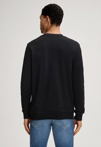 Schwarzer Langarm-Sweatshirt mit rundem Ausschnitt und gerippten Bündchen. Glatte Textur, schlichtes Design und keine sichtbaren Muster oder Logos.