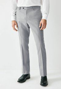 Grijze op maat gemaakte broek met een gladde textuur, platte voorkant en zijstrepen, gecombineerd met zwarte loafers. Geschikt voor formele gelegenheden.