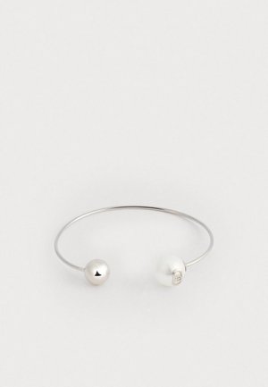 Srebrny bransoletka z gładką metaliczną kulą i białą perłą. Otwarta forma prezentuje minimalistyczną estetykę z delikatną fakturą.