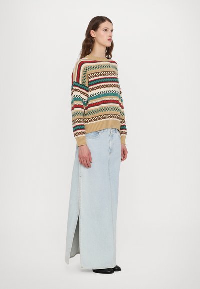 Maglione lavorato a maglia con motivi multicolori, caratterizzato da strisce, zig zag e trecce. Abbinato a una lunga gonna di denim chiaro con uno spacco laterale.