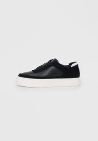 Sneaker nera con pannelli in pelle liscia e suede, lacci piatti, punta arrotondata e suola in gomma bianca. Logo distintivo sul tallone.