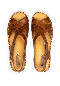 Sandalias de cuero marrón con un diseño entrecruzado, puntera abierta y acentos tejidos. Plantilla plana y acolchada con un interior natural en tono bronceado.